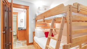 A bunk bed with a ladder, a wooden door, and a bathroom visible in the background. - Unique property | Steps to slopes | Free Parking (Whistler)