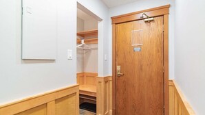 A hallway with a wooden door, a coat rack, and a small seating area. - Unique property | Steps to slopes | Free Parking (Whistler)