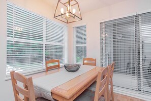 A dining area with a wooden table, chairs, a woven bowl, and a geometric light fixture. - Stylish | Steps to Blackcomb | Free Parking (Whistler)