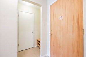 A hallway with a white door and a wooden door with a no-smoking sign. - Budget friendly Comfortable 1BDR | Close to Lifts (Whistler)