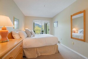 A bedroom with a bed, a dresser, a mirror, and a balcony with a view. - Budget friendly Comfortable 1BDR | Close to Lifts (Whistler)