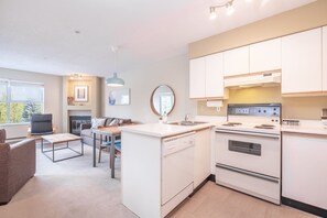 A modern kitchen with white cabinetry, a built-in oven, and a dining area with a table and chairs. - Budget friendly Comfortable 1BDR | Close to Lifts (Whistler)