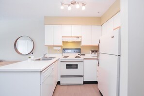 A modern kitchen with white cabinets, a stove, a refrigerator, and a sink. - Budget friendly Comfortable 1BDR | Close to Lifts (Whistler)