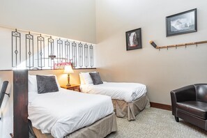 A hotel room with two beds, a desk, a chair, and a hockey stick on the wall. - Chic 2BDR + Loft | Perfect for Families or Friends (Whistler)