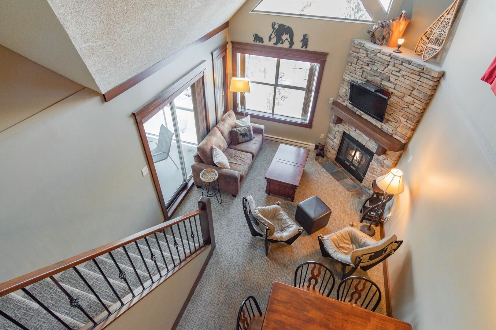 A loft-style living area with a stone fireplace, a sofa set, and a dining table.