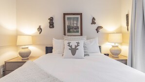A neatly made bed with white bedding, two bedside lamps, a framed picture on the wall, and decorative wall art. - Modern 2BDR + Loft | Close to Ski Lifts and Shops (Whistler)