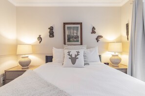 A neatly made bed with white bedding, two bedside lamps, a framed picture on the wall, and decorative wall art. - Modern 2BDR + Loft | Close to Ski Lifts and Shops (Whistler)