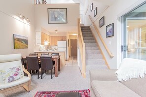 A modern interior with a dining area, kitchen, staircase, and seating space. - Modern 2BDR + Loft | Close to Ski Lifts and Shops (Whistler)
