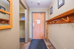 A hallway with a wooden door, a black mat at the entrance, and a wooden shelf with hooks. - Complex hot tub | Close to Lifts | Free Parking (Whistler)