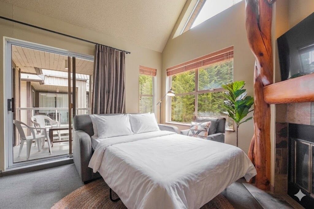 Un dormitorio con cama, chimenea y balcón con mobiliario exterior.