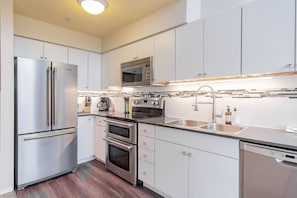 A modern kitchen with stainless steel appliances, a microwave, a sink, and a dishwasher. - Family friendly | Walk to Blackcomb | Hot tub (Whistler)