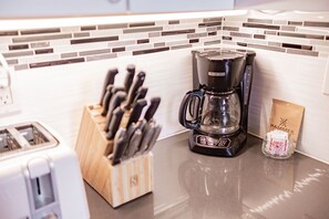 Eine Küchenarbeitsplatte mit Kaffeemaschine, einem Messerblock und einer Kaffeepackung.