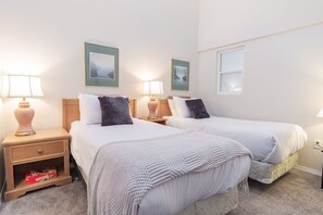 A hotel room with two beds, nightstands with lamps, a small shelf with a box, and framed pictures on the wall. - Family friendly | Walk to Blackcomb | Hot tub (Whistler)