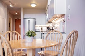 Un comedor con una mesa redonda de madera, cuatro sillas de madera y una planta en maceta.