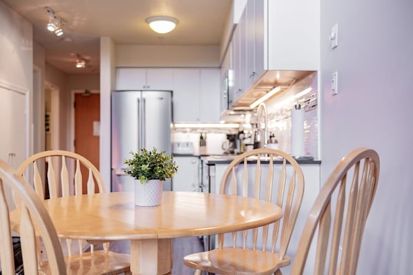 A dining area with a round wooden table, four wooden chairs, and a potted plant. - Family friendly | Walk to Blackcomb | Hot tub (Whistler)