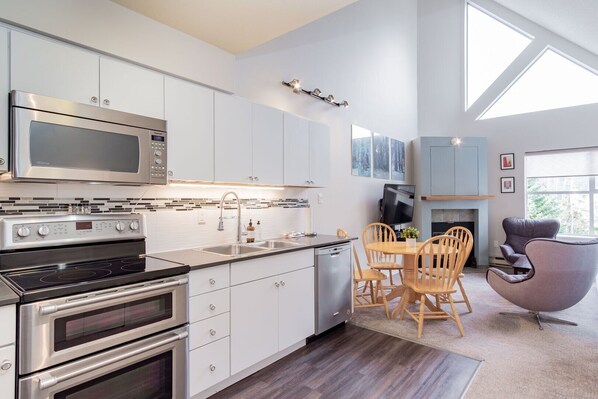 Una cocina moderna con electrodomésticos integrados, un comedor con sillas de madera y una chimenea.