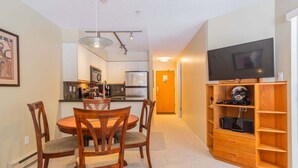 A compact living space with a dining area, kitchenette, and a TV stand. - Short walk to Blackcomb | Free parking | Hot tub (Whistler)