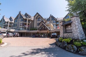 Eine mehrstöckige Lodge mit Steinverkleidung, Balkonen und einem Parkplatz.