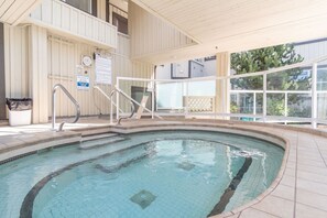 Ein Schwimmbecken mit einer gefliesten Terrasse, Metallhandläufen und einem Sicherheitsschild.