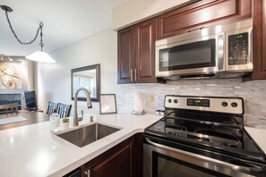 A modern kitchen with stainless steel appliances, a marble backsplash, and wooden cabinets. - Comfortable 2 Bdrm | Hot tub in complex | 5 min to Blackcomb (Whistler)