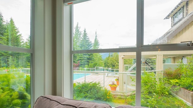 A room with a large window overlooking a pool and lush greenery. - Newly renovated 1 bedroom near Blackcomb Gondola - less than 5 min walk (Whistler)