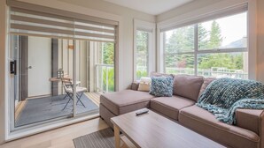 A modern living room with a sofa, a coffee table, and a view of a balcony. - Newly renovated 1 bedroom near Blackcomb Gondola - less than 5 min walk (Whistler)