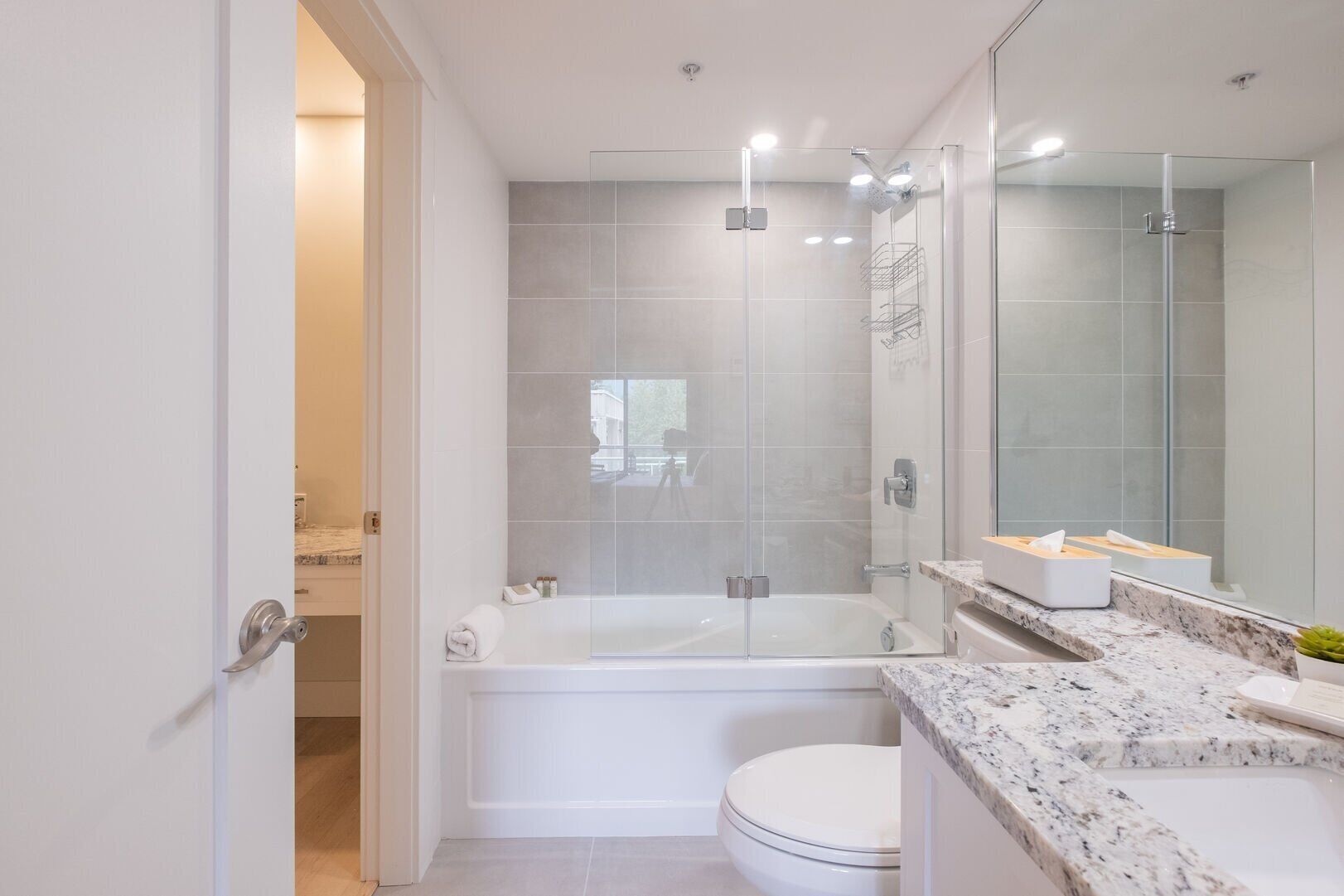 A modern bathroom with a glass-enclosed shower, a freestanding bathtub, and a marble countertop.