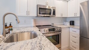 A modern kitchen with white cabinets, stainless steel appliances, and a granite countertop. - Newly renovated 1 bedroom near Blackcomb Gondola - less than 5 min walk (Whistler)