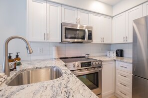 Una cocina moderna con armarios blancos, electrodomésticos de acero inoxidable y encimera de granito.