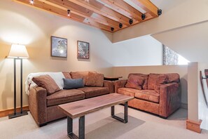 A cozy living room with a sofa, a coffee table, and a lamp. - Large groups and families | Free parking | Hot tub (Whistler)
