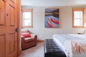 Ein Schlafzimmer mit einem Bett, einem Sessel, einer Bank und einem Bild von Kanus an der Wand.