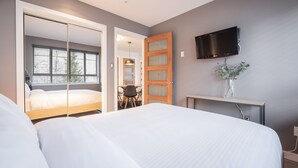 Ein Schlafzimmer mit einem Bett, einem Fernseher, einem Schreibtisch und einem Fenster.