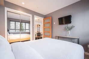 Ein Schlafzimmer mit einem Bett, einem Fernseher, einem Schreibtisch und einem Fenster.