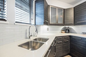 Een moderne keuken met een roestvrijstalen spoelbak, donkerhouten kastjes en een koffiezetapparaat.