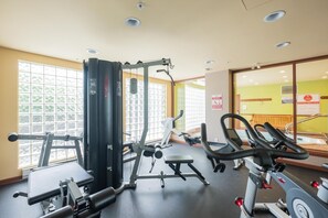 Un gimnasio con equipo de ejercicio, ventanas amplias y un espejo.