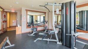 Ein Fitnessstudio mit Trainingsgeräten, Spiegeln und einer Tür mit einem Ausgangsschild.