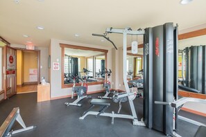 Ein Fitnessstudio mit Trainingsgeräten, Spiegeln und einer Tür mit einem Ausgangsschild.