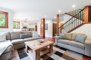 A spacious living area with two sofas, a coffee table, and a staircase. - Spacious 2BDR on Blueberry Hill | Pets | Complex Hot Tub | BBQ (Whistler)