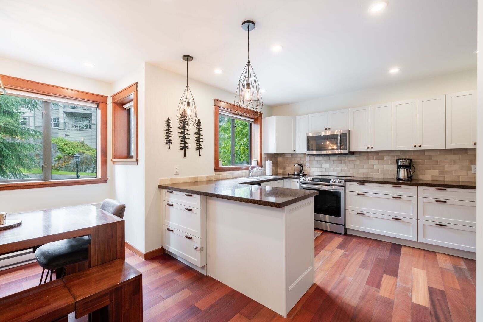 A modern kitchen with white cabinetry, a central island, and a dining area with a bench.
