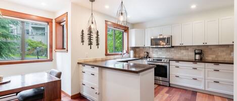 A modern kitchen with white cabinetry, a central island, and a dining area with a bench.
