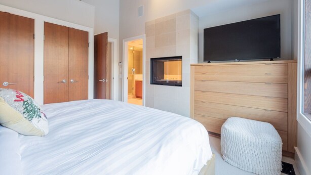 Een slaapkamer met een bed, een televisie, een houten kledingkast en een zichtbare badkamer door een geopende deur.