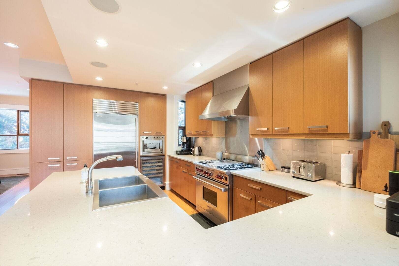 A modern kitchen with wooden cabinets, stainless steel appliances, and a central island.