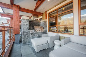 An outdoor seating area with stone walls, a grill, and a view of a snowy landscape. - Luxury | AC | Private Hot Tub | BBQ | Pet friendly (Whistler)