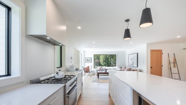 Een moderne keuken met een centraal eiland, witte kasten en een groot raam.