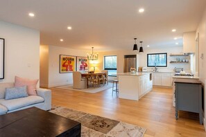 A spacious living area with a sofa, coffee table, and a dining area with a chandelier.