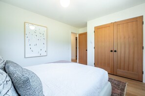 A bedroom with a bed, a framed picture on the wall, and a wardrobe. - Secluded house in Pemberton | Mount Currie Views | Sauna (Whistler)