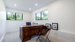 Een vergaderruimte met een houten tafel, twee stoelen en ingelijste foto’s aan de muur.