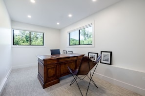 A modern office space with a wooden desk, a leather chair, and framed pictures on the wall.
