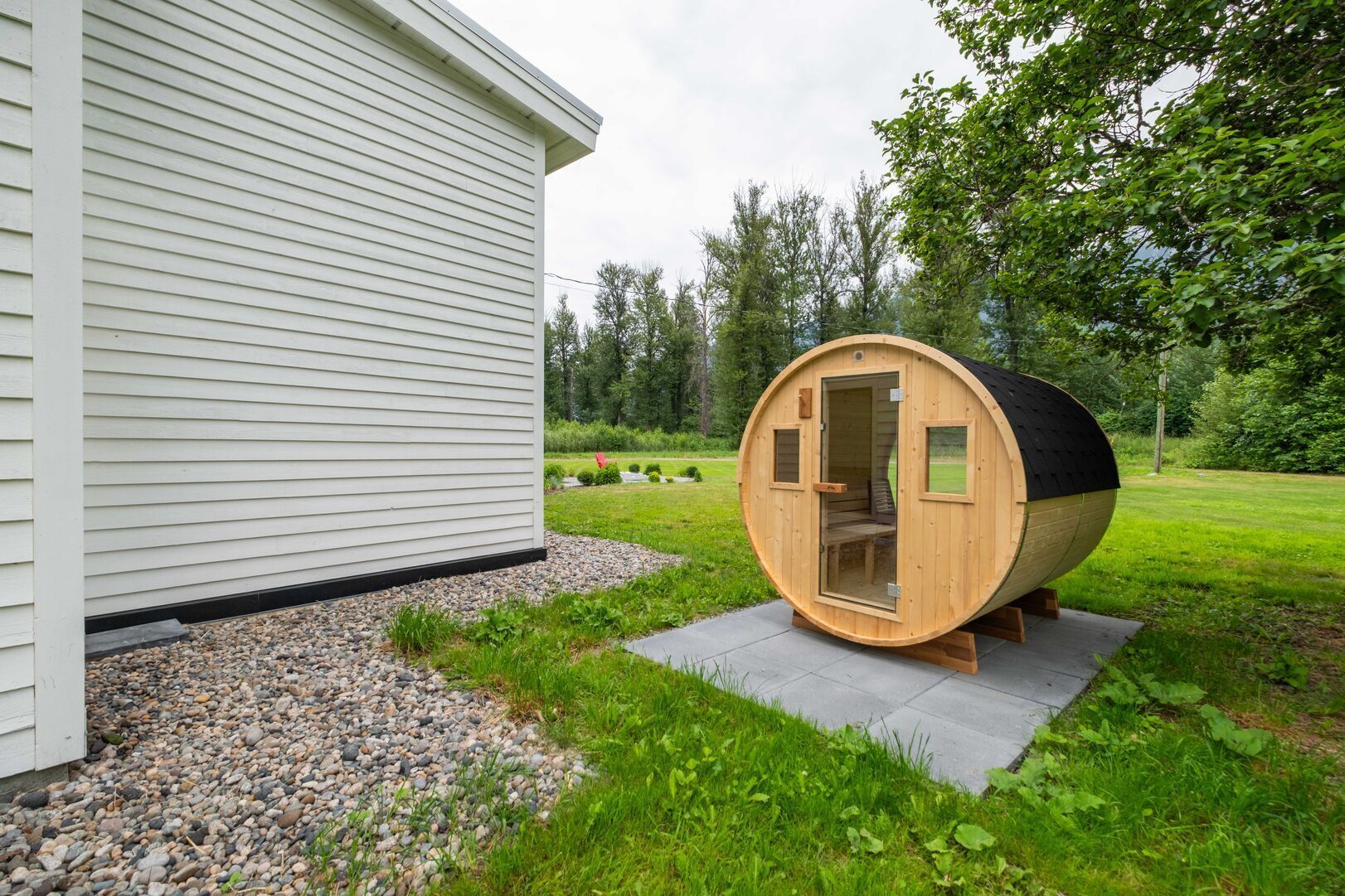 Una sauna amb porta, situada en un camí de grava al costat d'una casa.