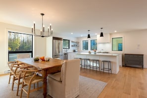A modern kitchen with a wooden dining table, bar stools, and a large island.